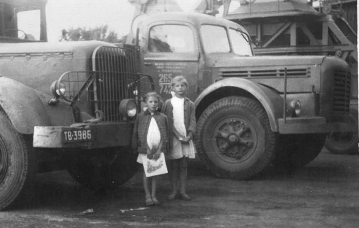 Dwie dziewczynki stoją na&nbsp;tle dużego samochodu ciężarowego. Fotografia czarno-biała