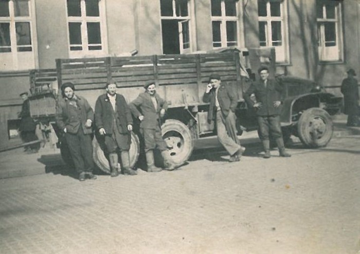 Pięciu mężczyzn na&nbsp;tle ciężar&oacute;wki. Fotografia czarno-biała