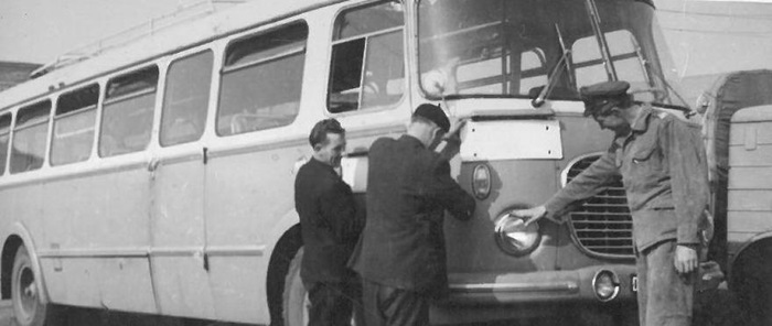 Trzech mężczyzn ogląda autobus. Fotografia czarno-biała