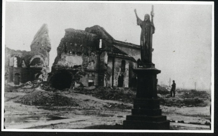 czarno-biełą zdjęcie przedstawia figurę Chrystusa na&nbsp;tle zniszczonych budynk&oacute;w