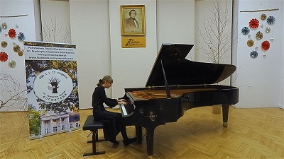 Młoda pinistka w czarnym stroju gra na fortepianie na scenie Pańśtwowej Szkoły Muzycznej w Sochaczewie