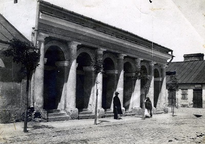 historyczne zdjęcie kramnic miejskich w Sochaczewie - czarno biała fotografia, widoczne dwie osoby przed budynkiem